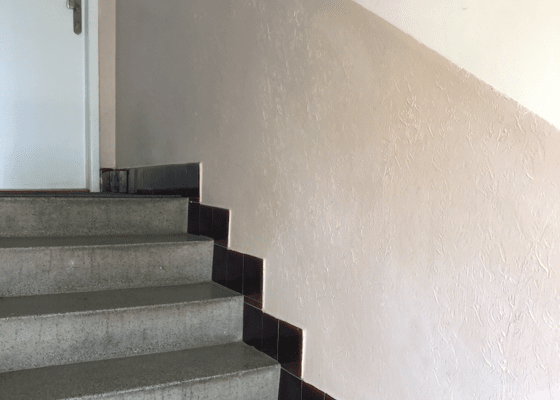 Pokládka kamenného koberce na zeď podél schodiště