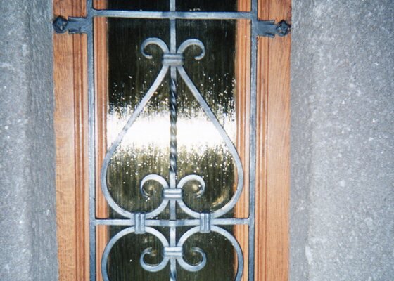 Vchodové dveře a okno s kovanými mřížemi.