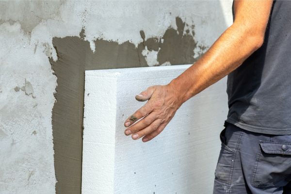 řemeslník přikládá polystyren na stěnu domu 